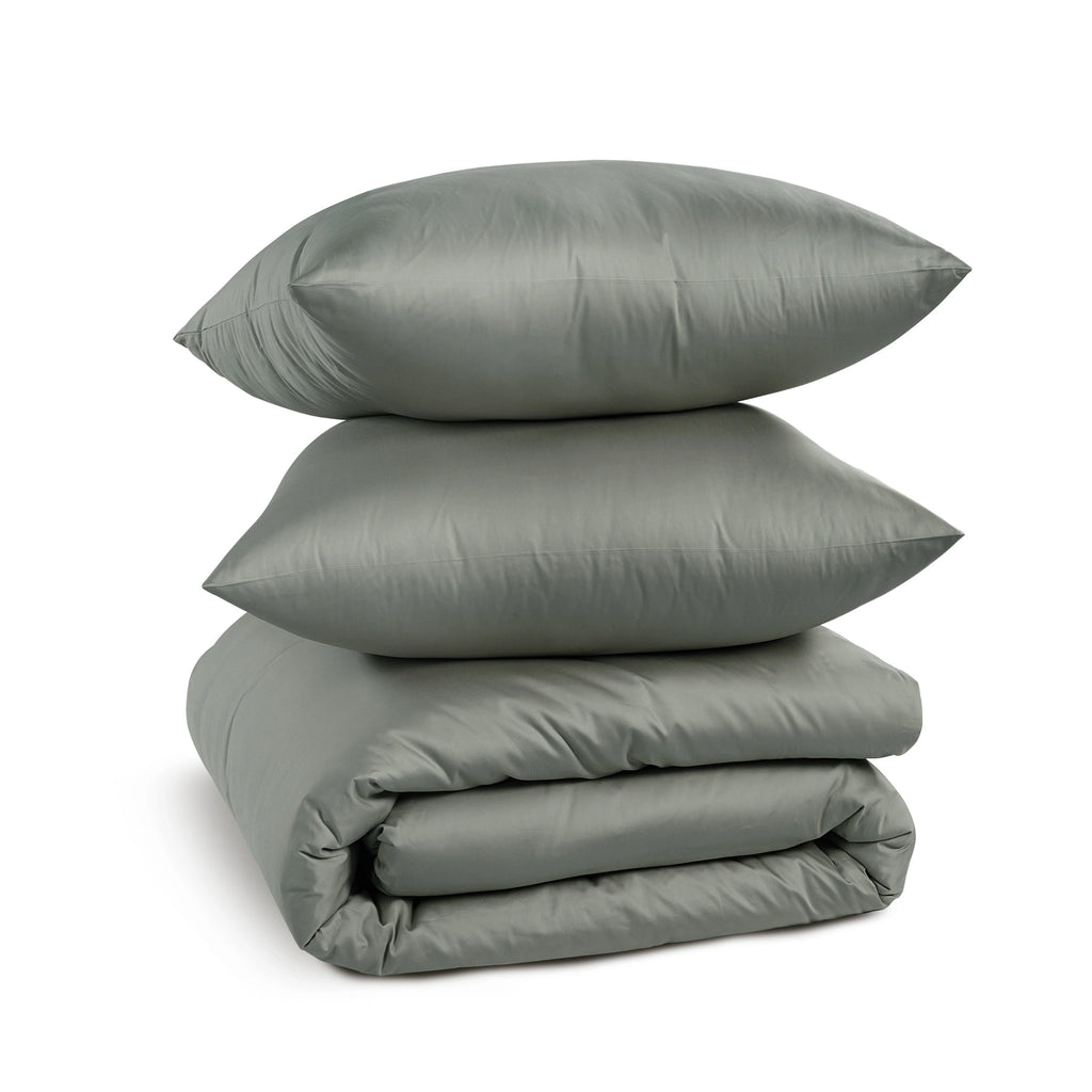 A stack of three gray bedding pieces, including two pillows and a folded comforter or duvet, photographed on a clean white background.