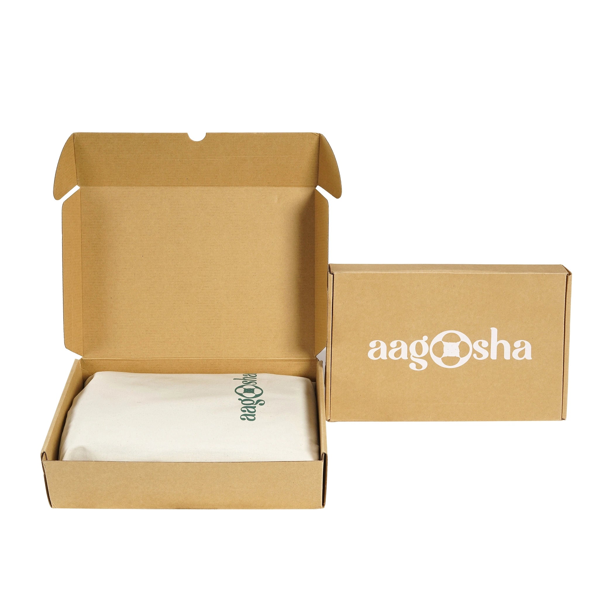 A kraft brown cardboard box shown open with a white cloth inside, alongside the closed outer box printed with the white 'aagasha' logo. The cloth has a small green script logo.